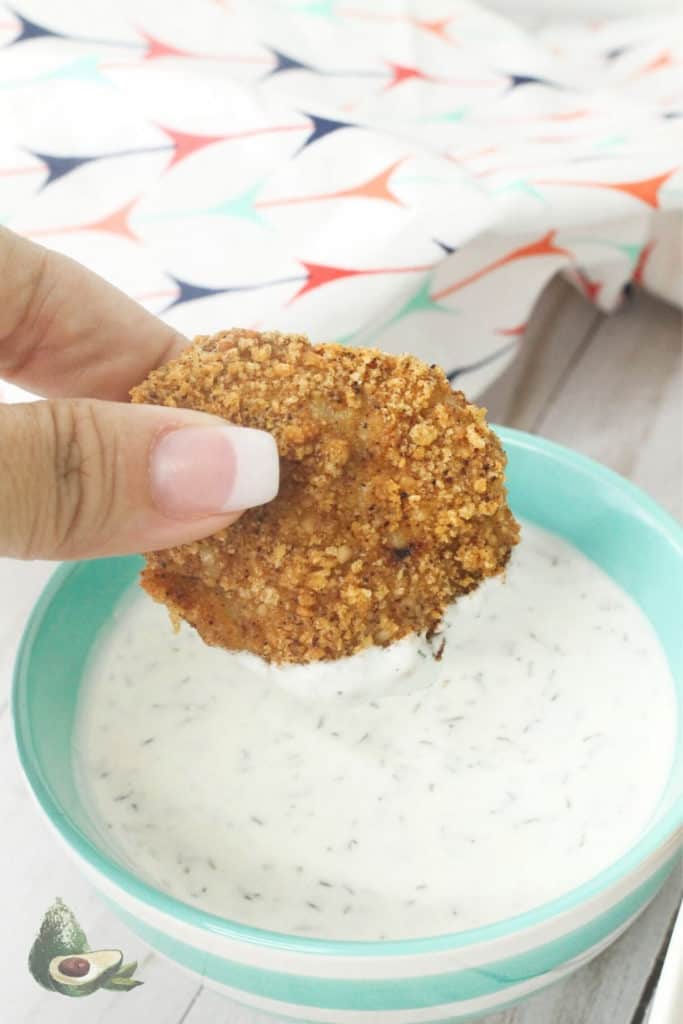 womans hand dipping chicken nugget in ranch dressing