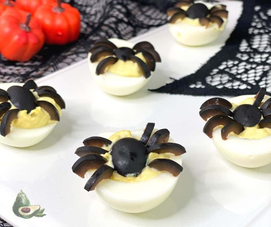 spider deviled eggs with pumpkins in the background 